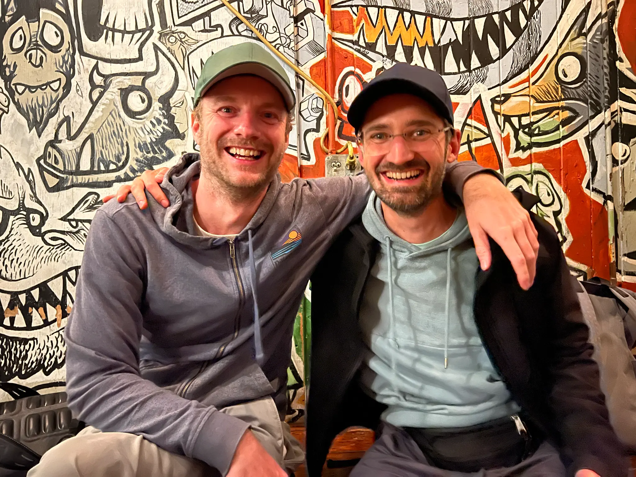 Nils and Julian in front of a tagged wall
